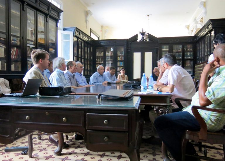 An AAAS-led group meets with its hosts at the Cuban Academy of Sciences in Havana. A group of people sitting around a table talking, in a boardroom.